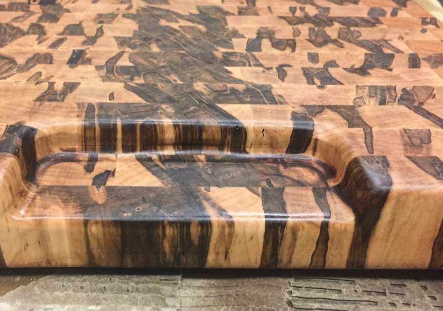 Thick end-grain board in spalted maple and walnut with a carved recessed handle along the edge
